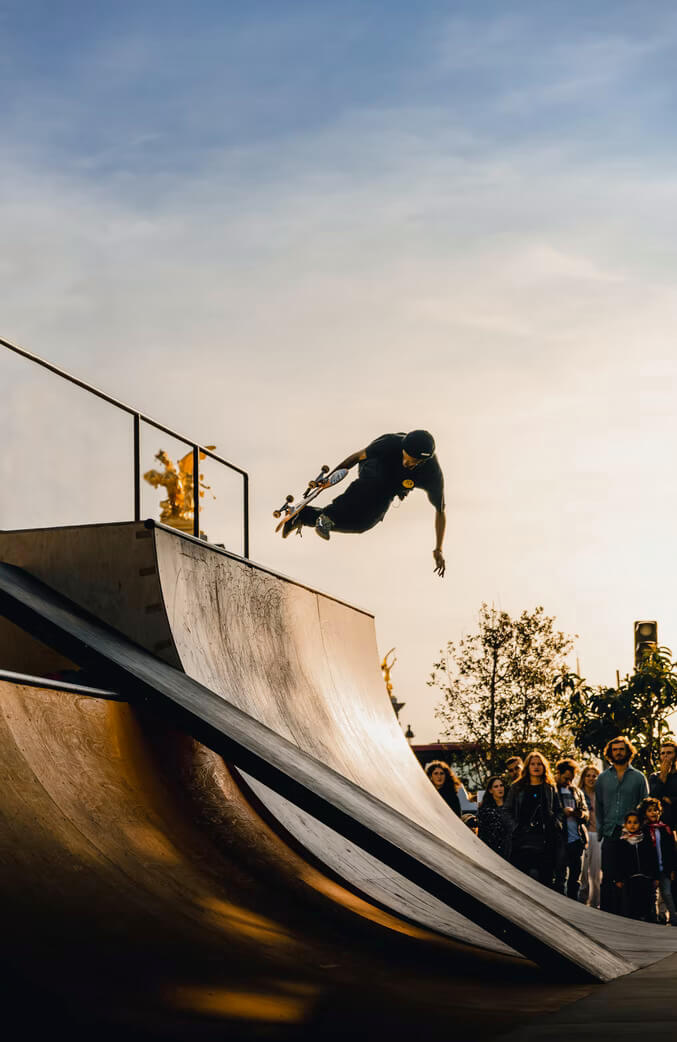 Man performing skateboarding tricks on a halfpipe with crowd watching