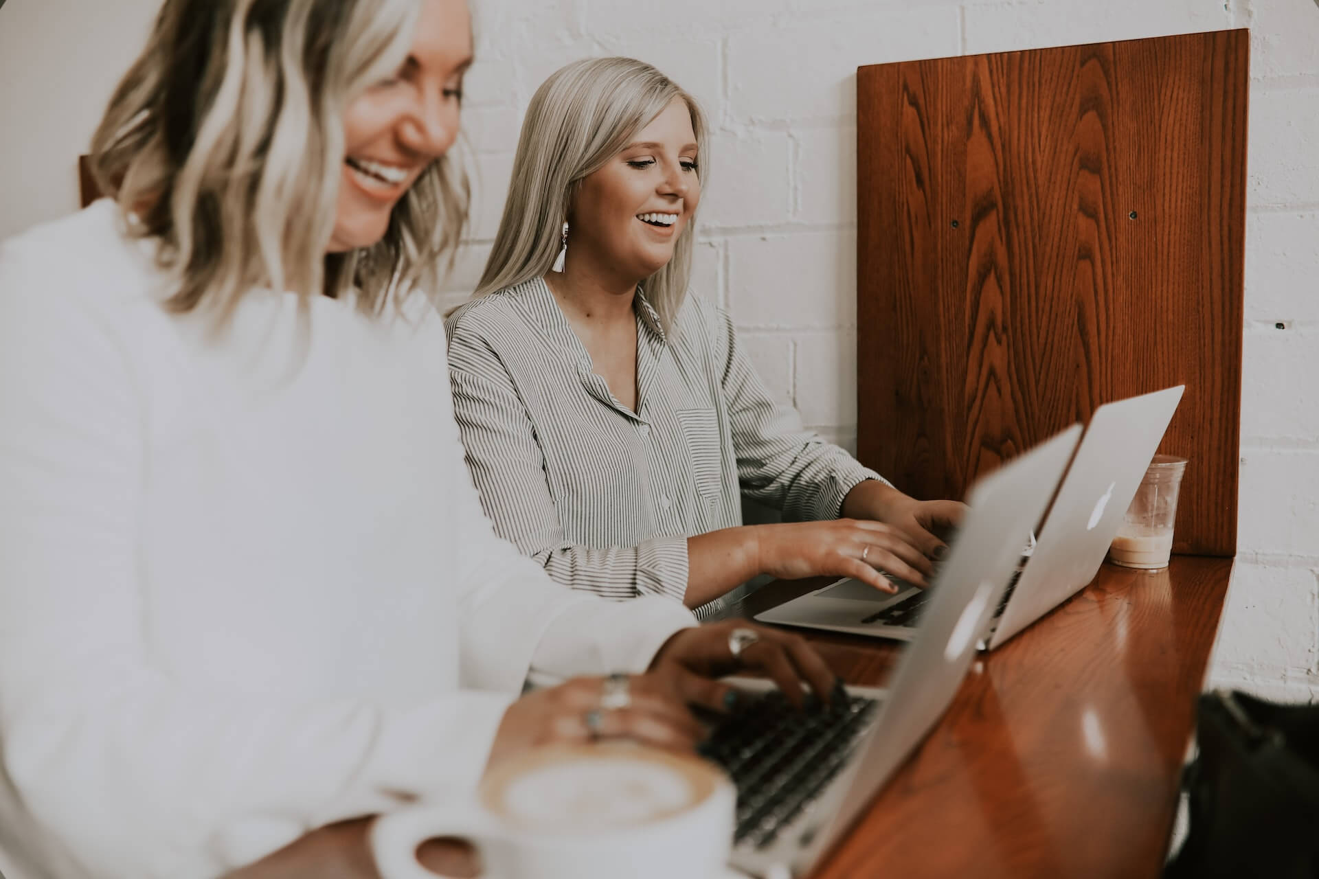 two women smiling at laptops